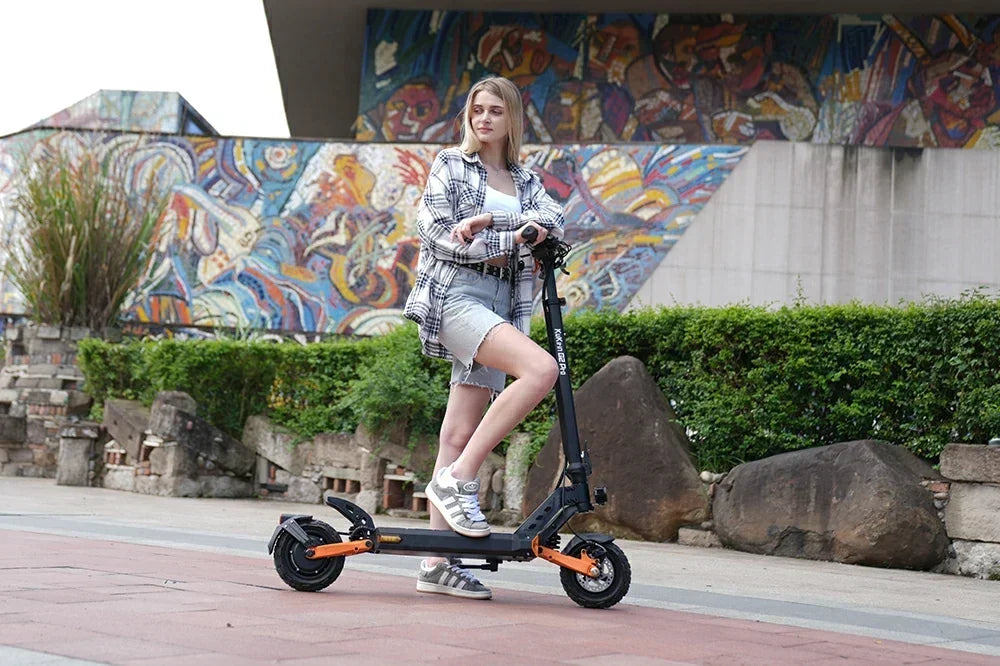 Young woman posing with Kukirin G2 Pro electric scooter in front of colorful graffiti mural.