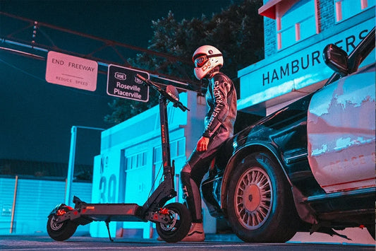 Helmeted rider leans on vintage car beside Kukirin G4 electric scooter in neon‑lit night city
