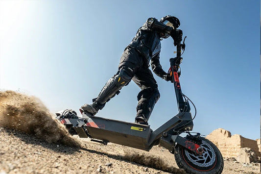 Rider in full protective gear drifting on Kukirin G2 Ultra off‑road electric scooter kicking up desert sand