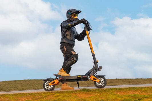Full‑gear rider standing on Kukirin G3 Pro off‑road electric scooter on open grassy highland