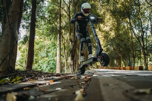 Dynamic low-angle action shot of rider wheeling dark Kukirin G4 high-performance electric scooter along shaded forest trail.