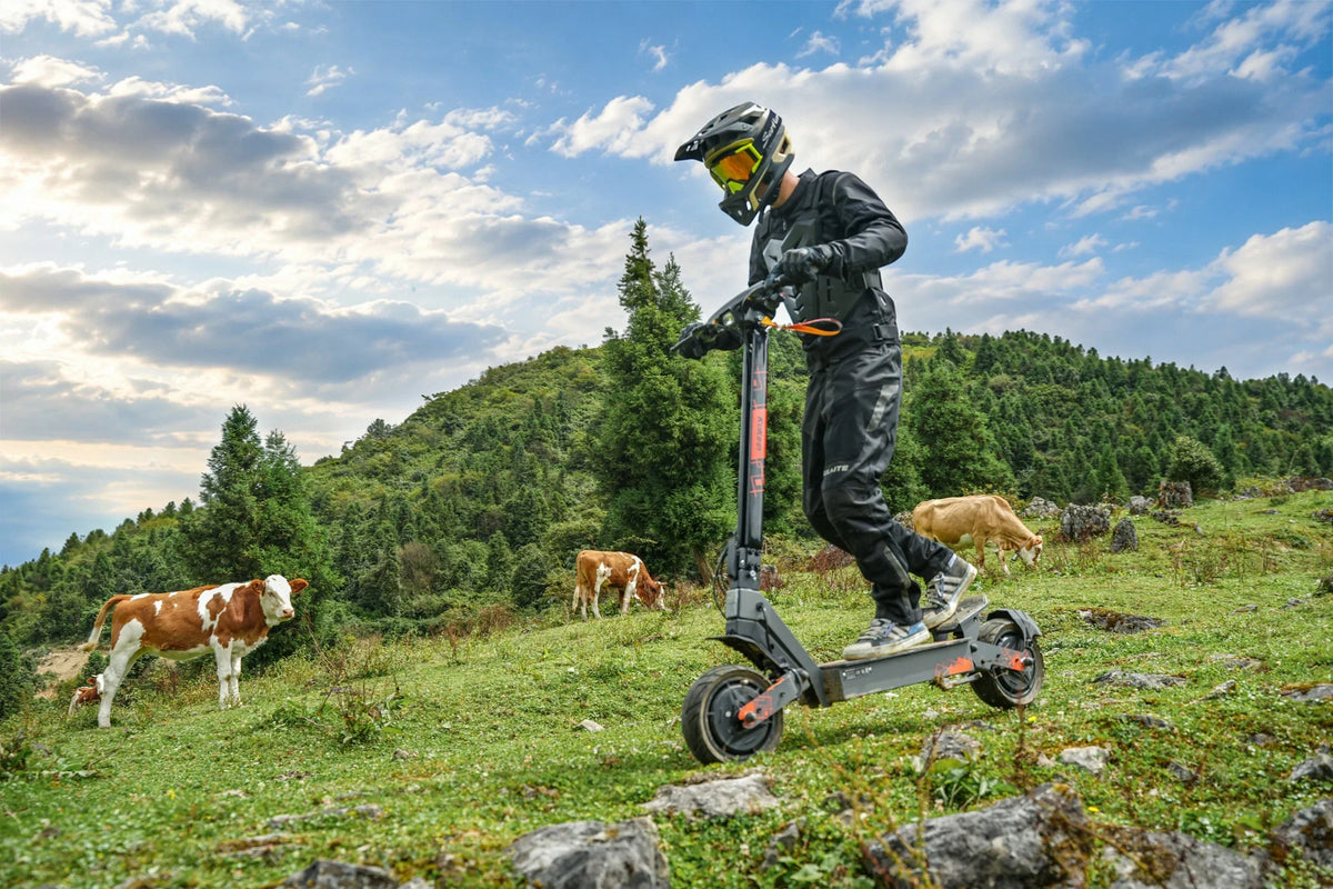 Rider on Kukirin G4 Ultra electric scooter on green mountain meadow with cows